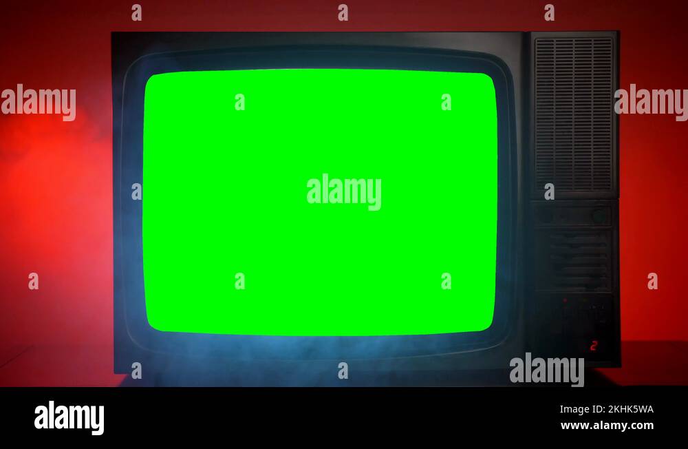 Old vintage television with blinking green screen on red background