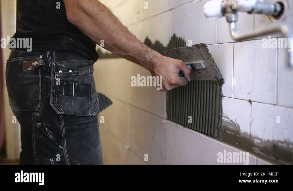 Laying Ceramic Tiles. Tiler placing ceramic wall tile in position over