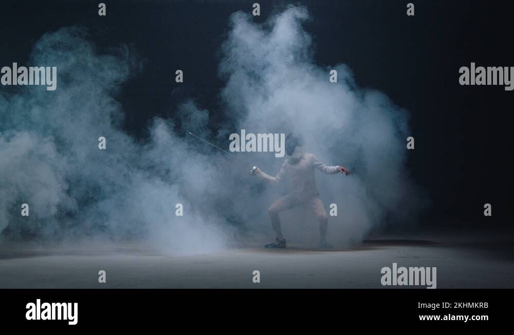 Professional fencer in uniform practicing maneuvers with sword in dark