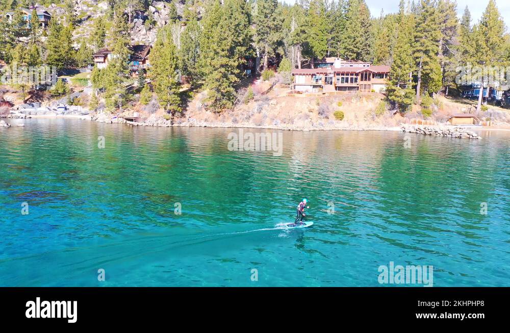 2020 a man rides a hydrofoil efoil electronic surfboard across Lake