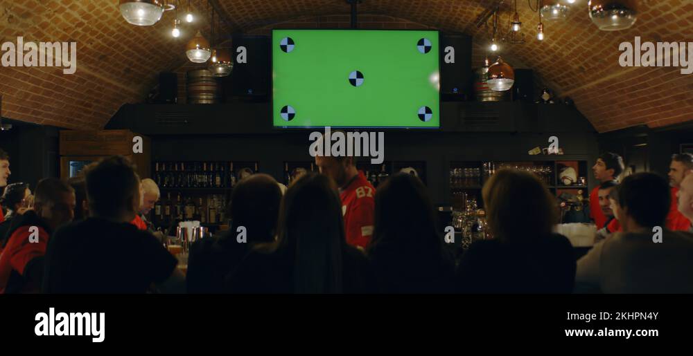 Fans watching a game on TV in a sport pub, green screen chroma key