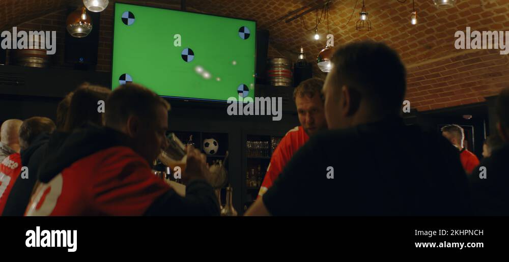 Fans watching a game on a TV in a sport pub, goal celebration, green
