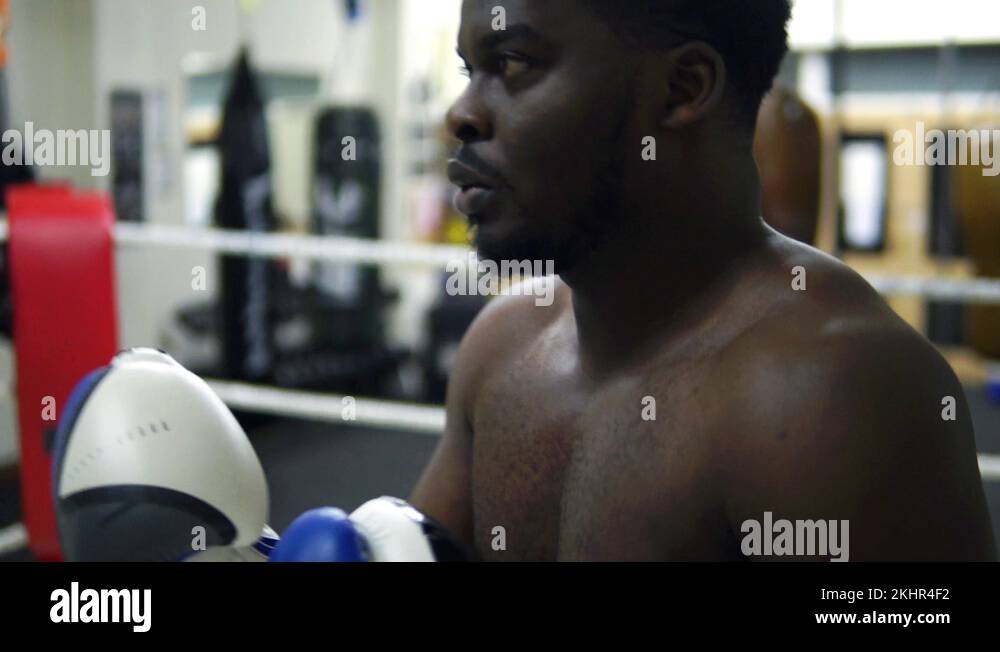 Cinematic Black Male Boxer Training With Pads In Boxing Ring Stock