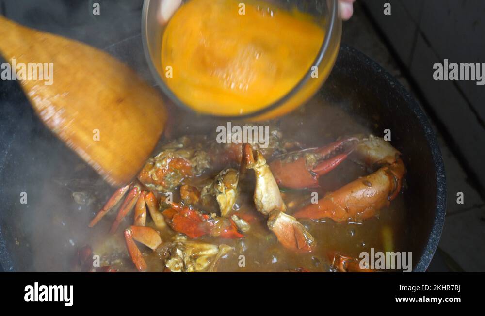 Chef cooking Singapore Chilli crab signature dish adding egg yolk Stock