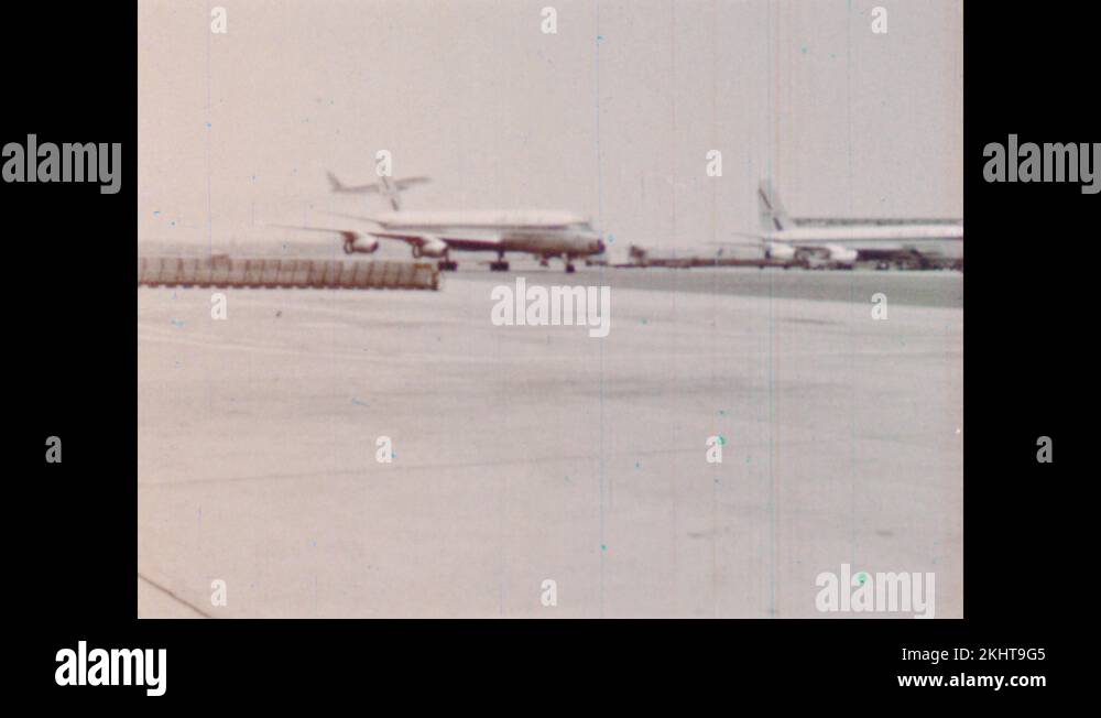 1960s Planes sit and taxi on runway of airport. Planes sit on runway