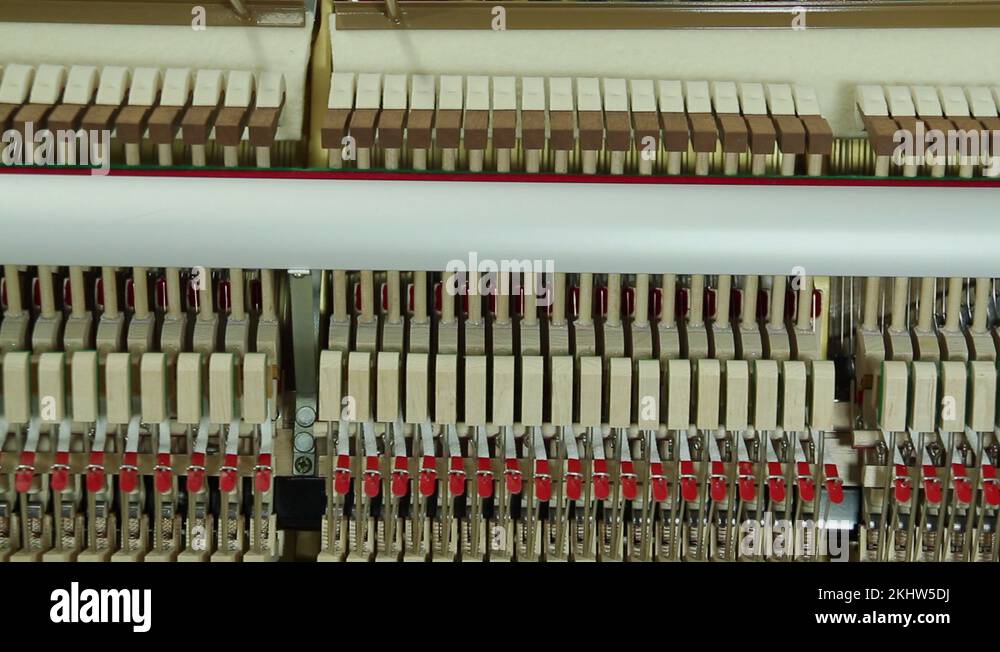 Inside of upright piano, hammer of piano keys is hitting the strings