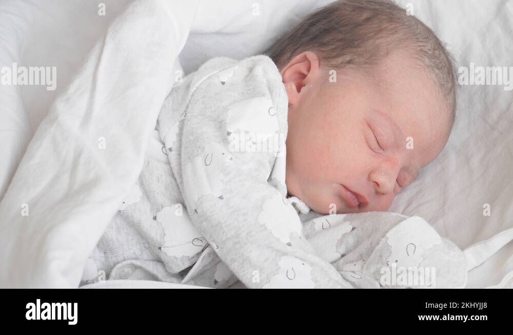 Female hands put a hat on a newborn baby on a white background. Mom