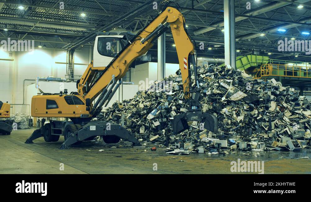 Mechanical loader is grabbing garbage and putting it into a pile