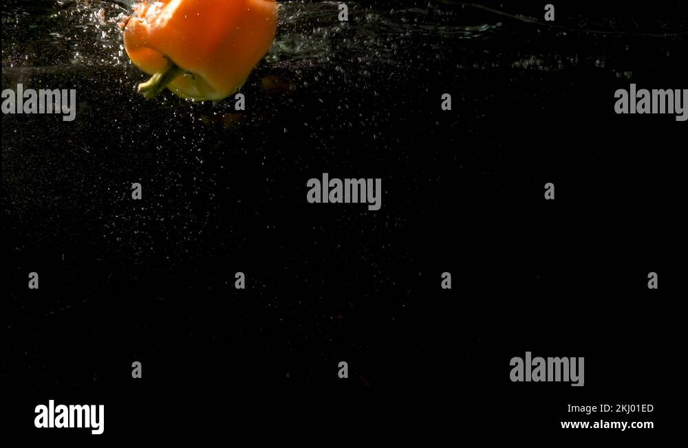 Two peppers floating on the water surface leaving dark clear water ...