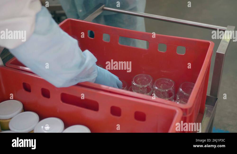 A food factory worker puts glass jars in a box. Stages of manual labor