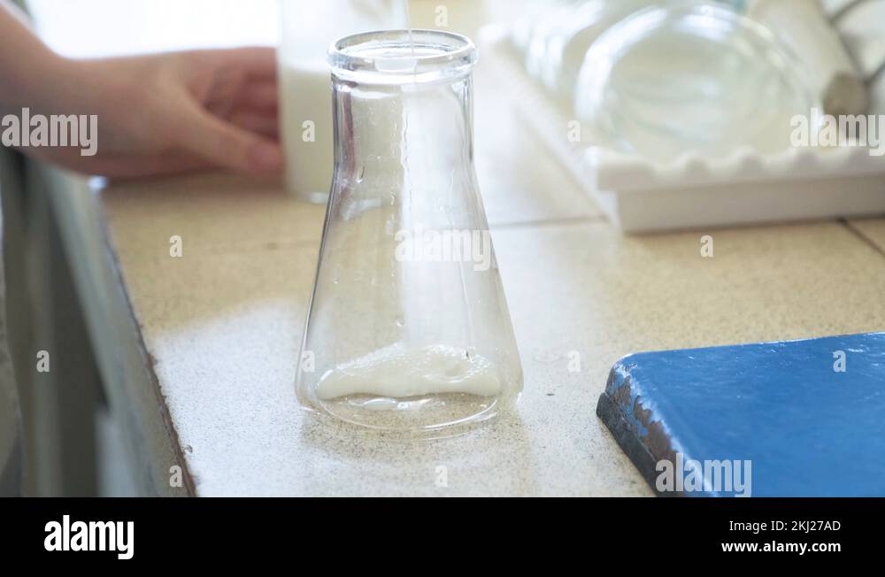 The glass flask is filled with milk in small doses. Samples in the