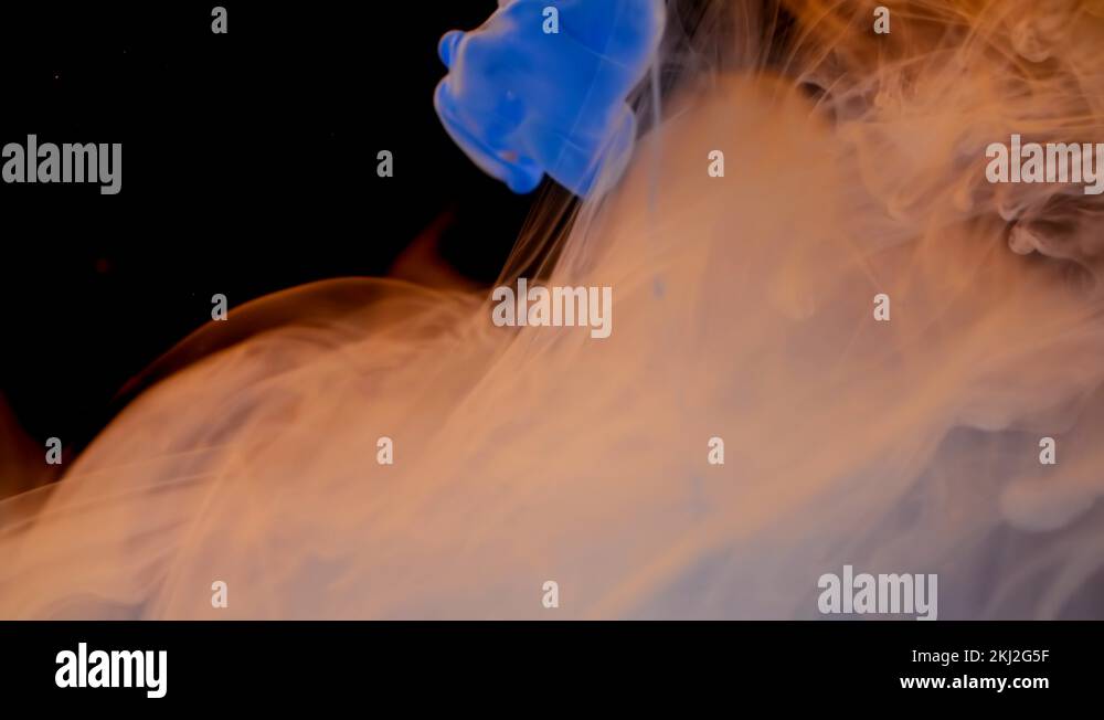 Blue and orange ink spreads in water, colored smoke spreading