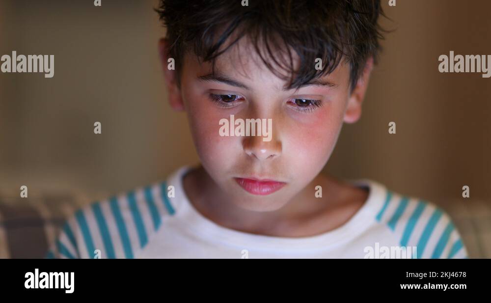 Boys in front of tablet screen with blue light glowing on face at night