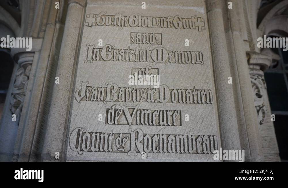 Camera tilts down on gothic script engraving on stone wall expressing a ...