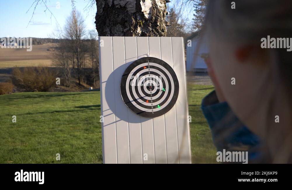 Young woman throws a dart at an outside target in a game for fun but