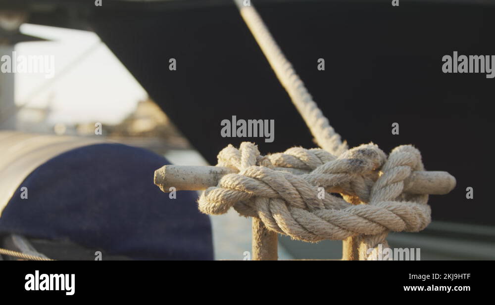Close up detail of a knot in a rope securing a boat tied to a jetty ...