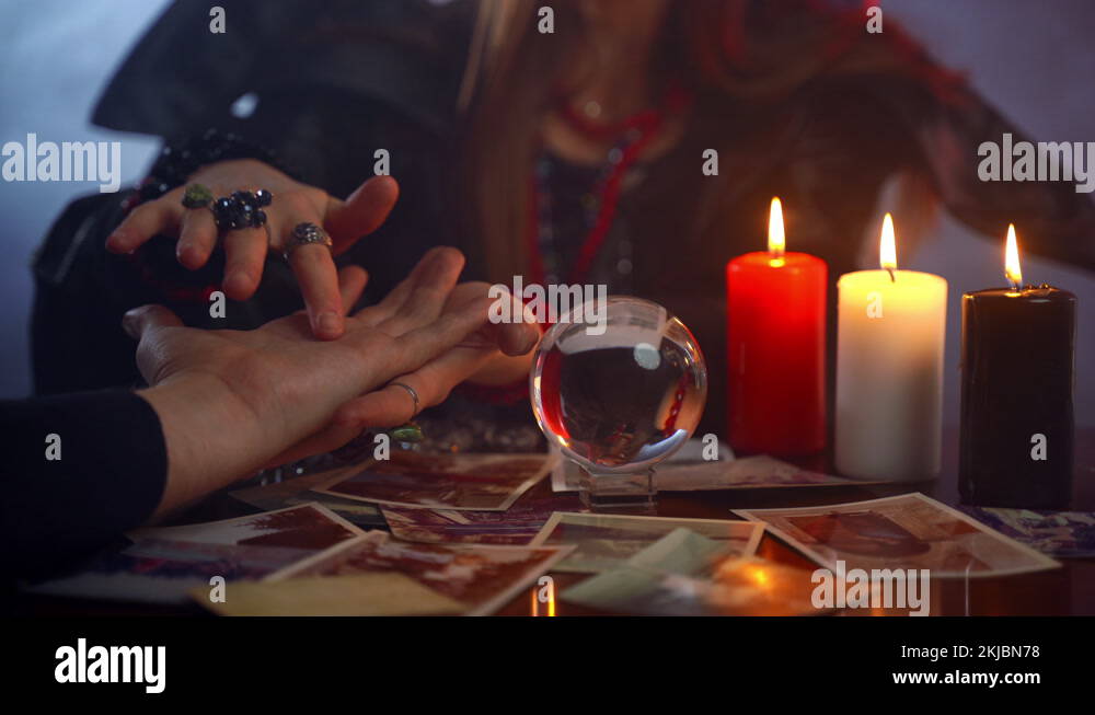 Young witch fortune teller reading fortune lines on male palm or hand