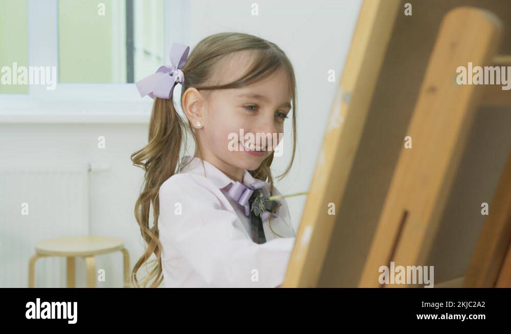 little girl paints a picture and looks at the camera. Happy little girl ...