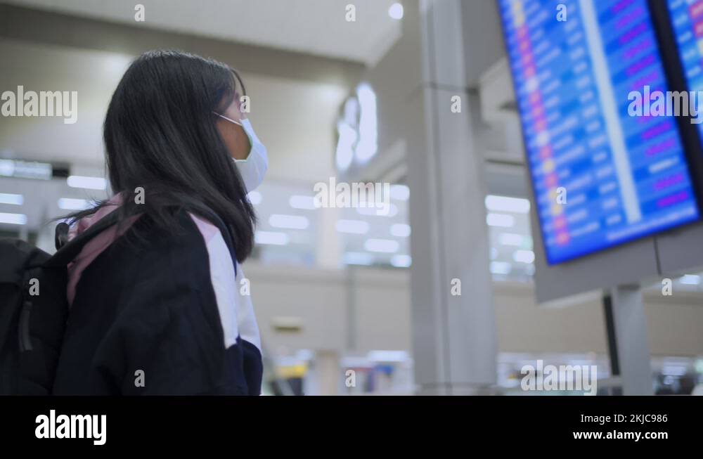 asian-female-wear-mask-look-up-to-flight-time-table-board-at-airport