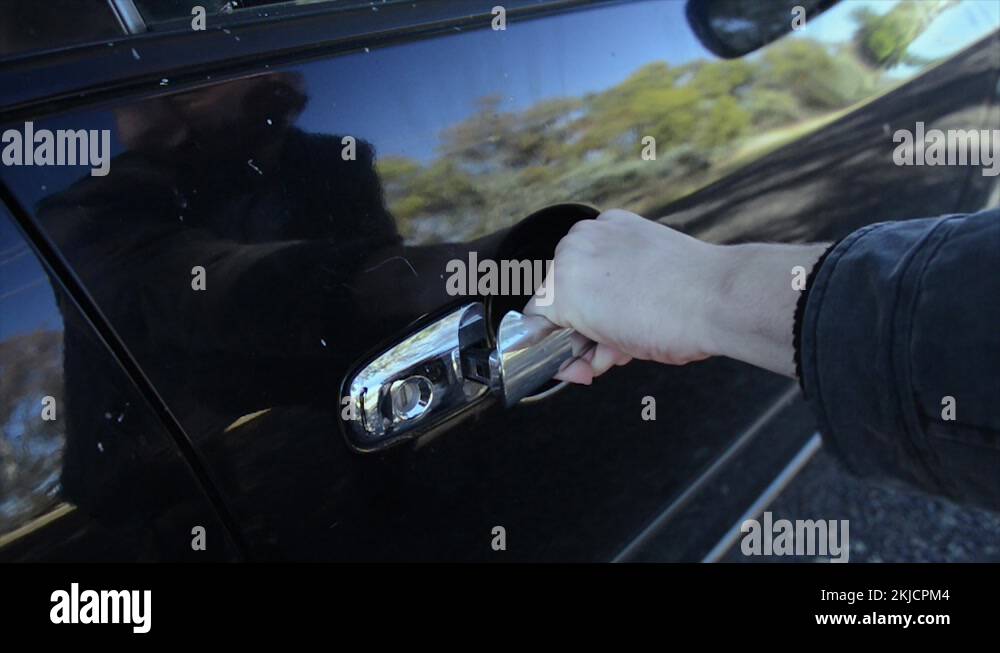 Masked man trying to jam the car handle and force to open the door