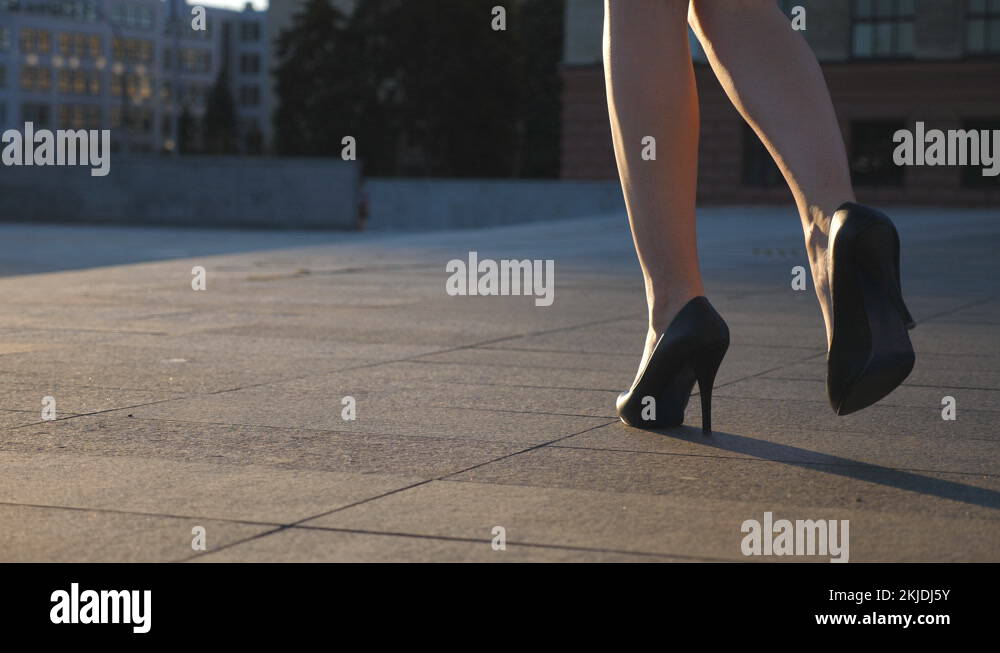 Female legs in high heels shoes walking in the urban street. Feet of
