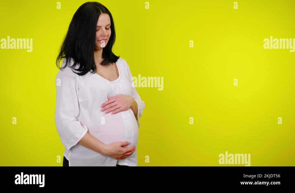 Young pregnant woman with is massaging belly, the child is pushing and