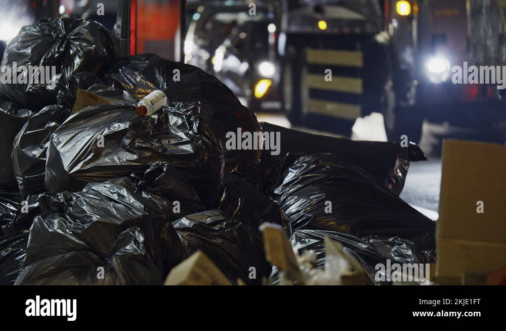 Plastic bags garbage pile, New York City street by night, dump disposal