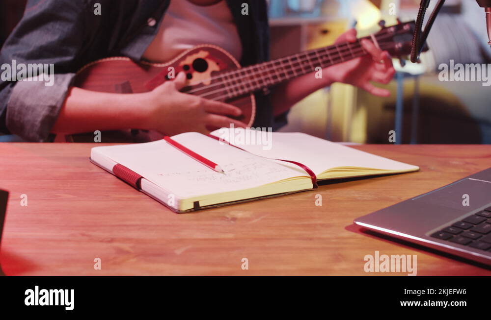 Female Asian Songwriter Playing the Guitar and Writing in Notepad Stock ...