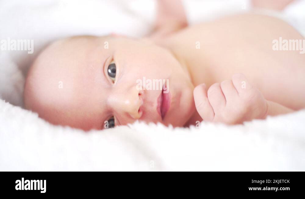 Face close up to the newborn. Baby with open eyes and mouth. girl lying