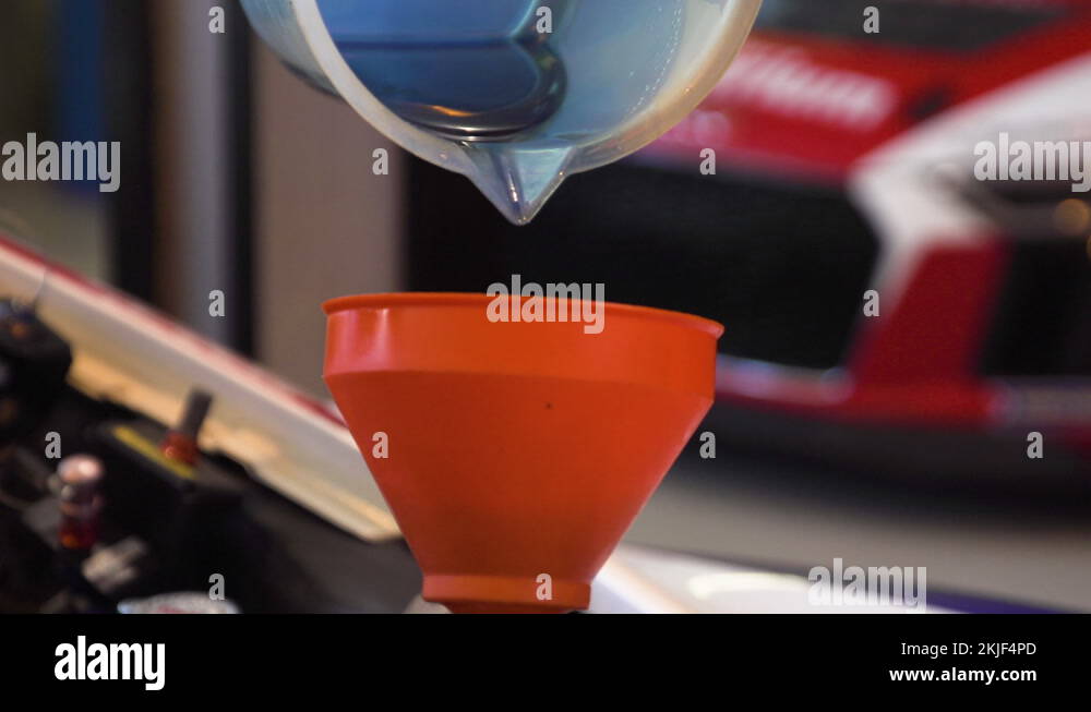 Adding engine coolant, sport car engine refill. Red sport car in the