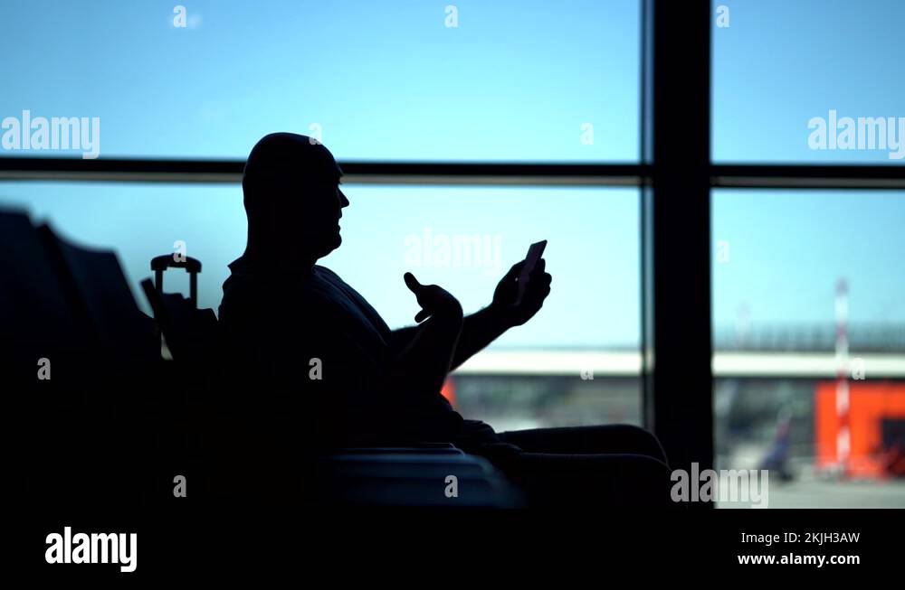 man is using video call in airport terminal, waiting for boarding