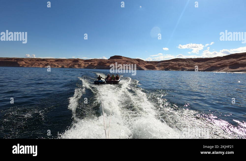 Friends on float tubes behind fast boat Lake Powell Utah 4K Stock Video