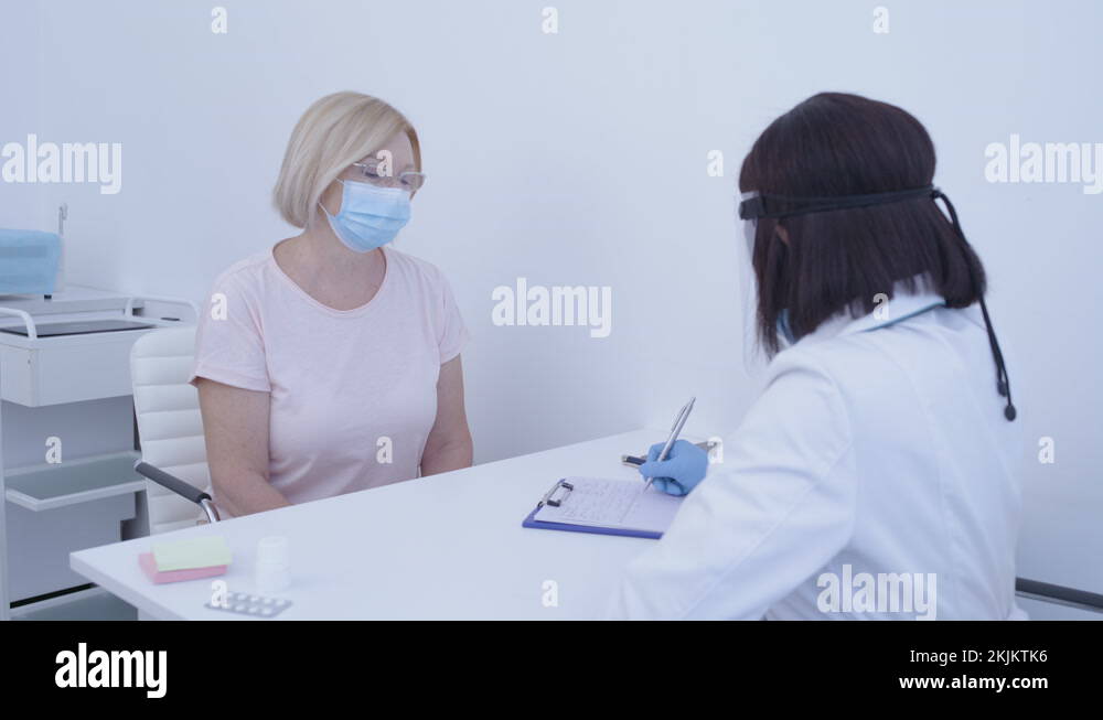 Nurse examining patient, checking temperature on forehead, symptoms of ...