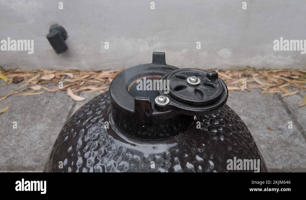 Adjusting the vent to control smoke rising from a kamado bbq smoker in