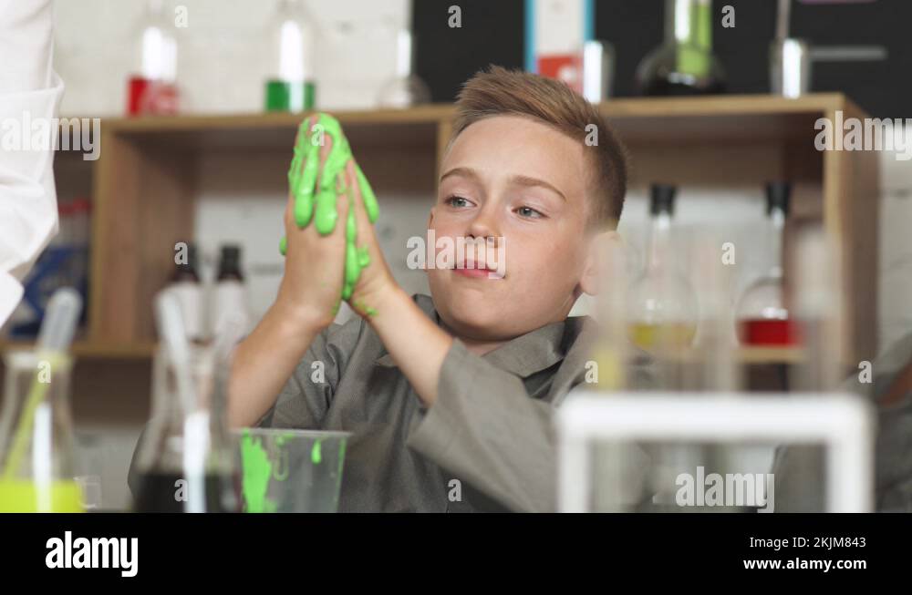 Laboratory experience in a chemistry lesson, the boy playing with a light green Stock Video