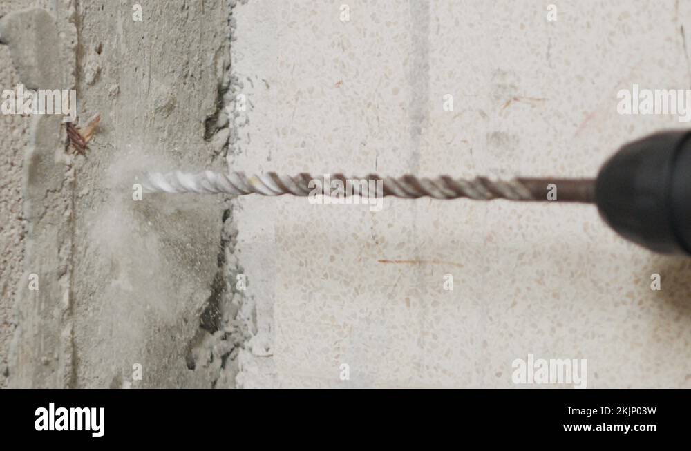 Man drilling hole in concrete wall. Repair works indoors in slow motion