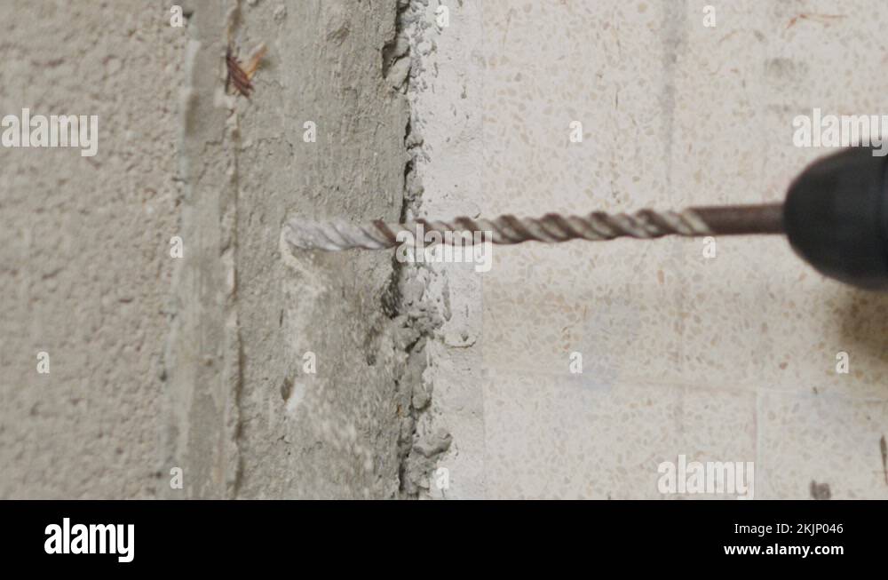 Man drilling hole in concrete wall. Repair works indoors in slow motion