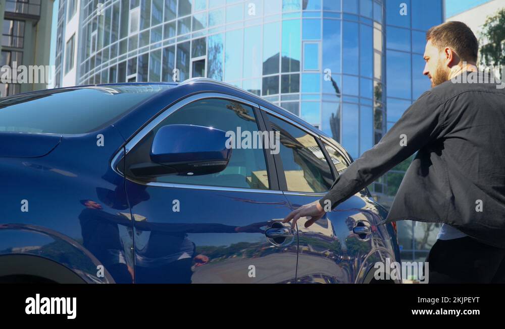 Young man sitting into the car salon and closing door. Car dealership