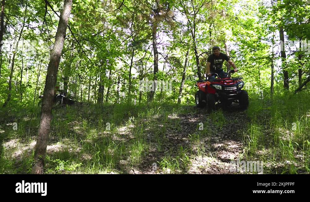 Guys, men on an ATV ride down a small hill. Quad bikes in the forest