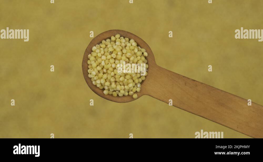 Spoonful of millet grains over the rotating defocused millet seeds. Top