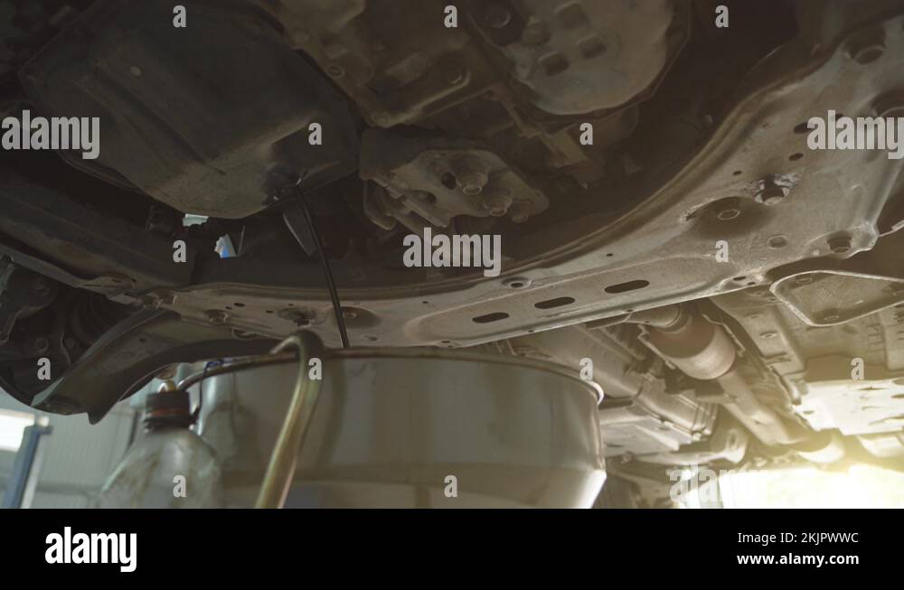 Worker drains old motor engine oil to replace in car service, close up
