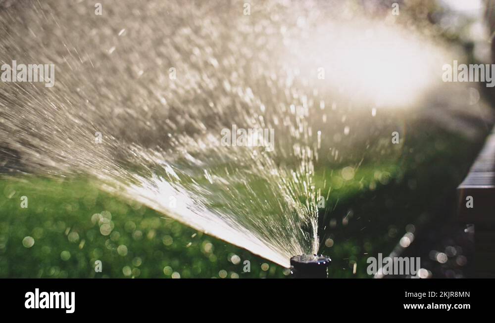 Watering the grass. SLOW MOTION. Water spraying out of sprinkler on the