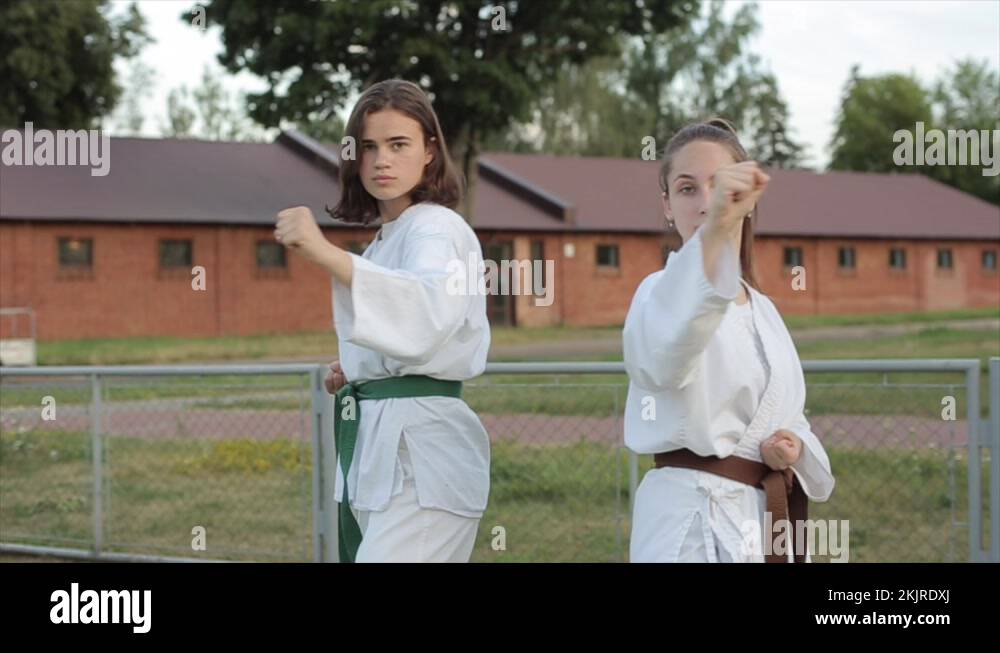 Two young girls in white kimonos demonstrate standard fighting karate
