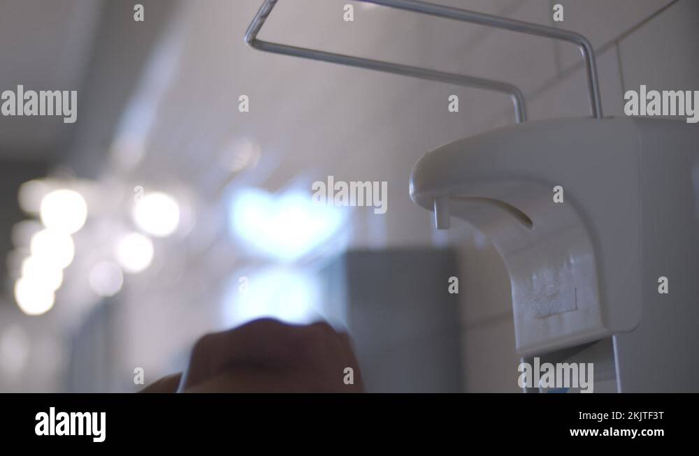 Close up human washing hands with alcohol sanitizer dispenser in public