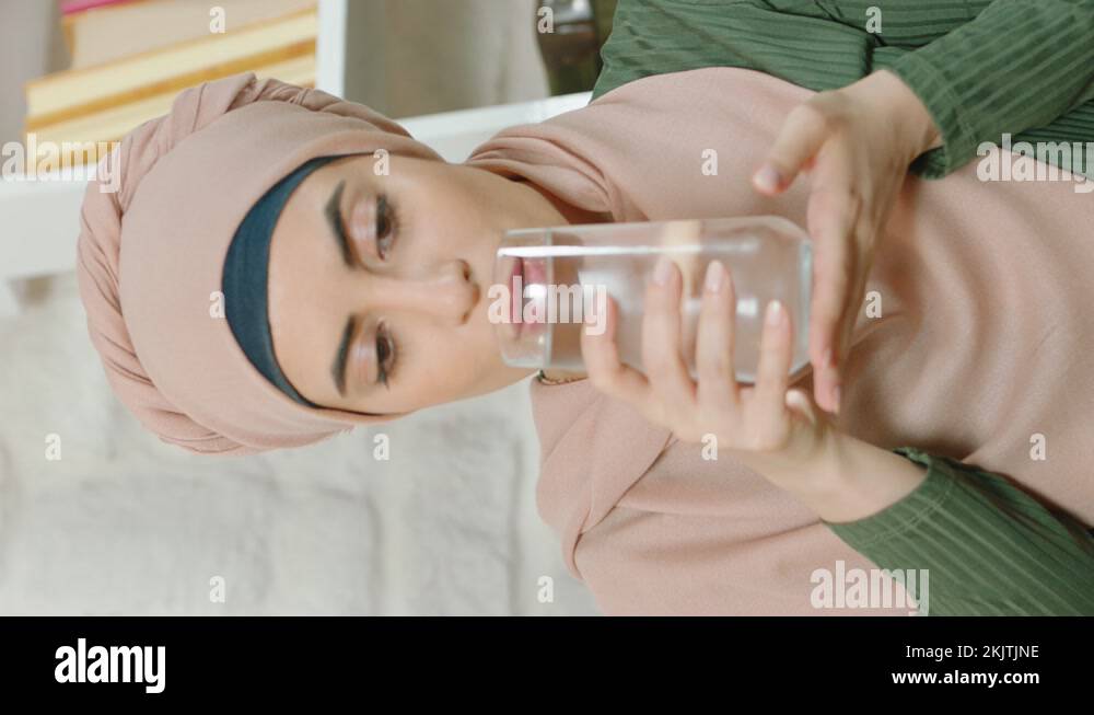 Young muslim woman in hijab is drinking water while praying with glass ...