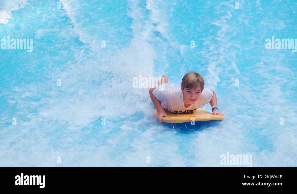 Boy surfing on bodyboard at waterpark. Young boy having fun with water