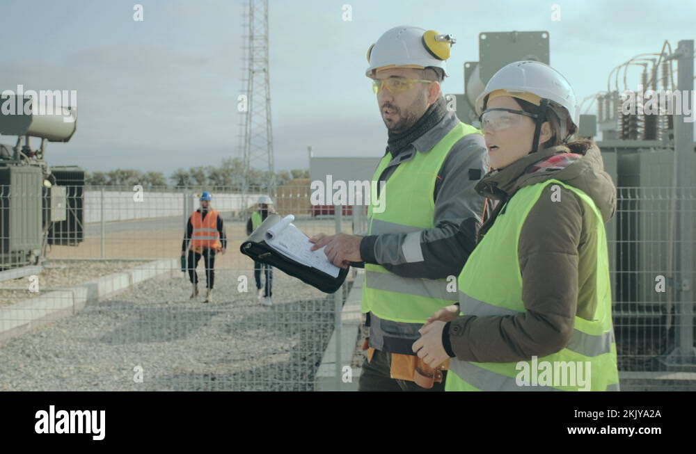 Power engineers walk along the transformers and discuss the construction project Stock Video