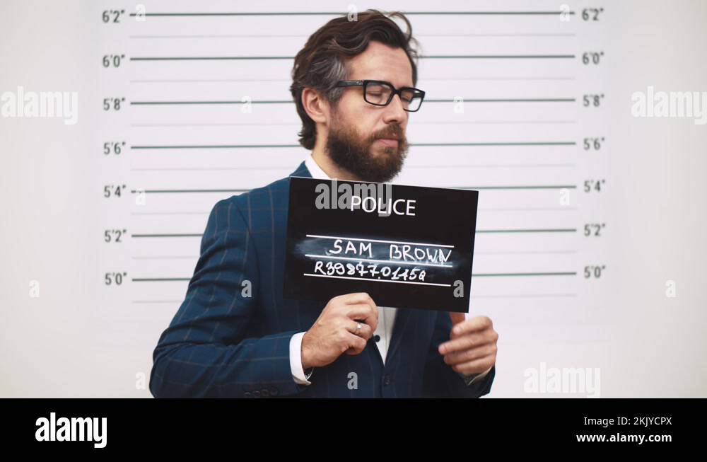 Guilty businessman in police station posing for mugshot with placard ...