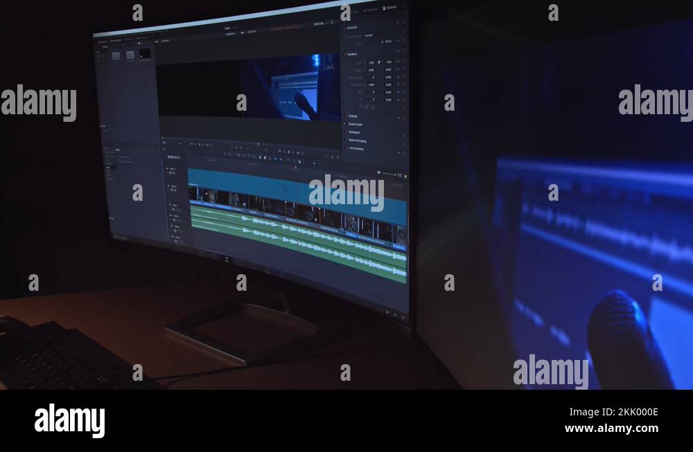 Young man editing a video clip on two monitors in studio. Dark night