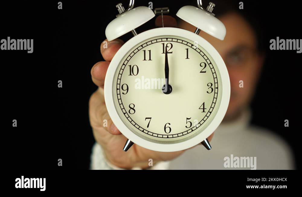 12 o'clock. Human hand holding alarm clock that showing twelve o'clock ...